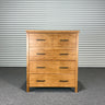Wooden dresser with multiple drawers against a corrugated metal wall.
