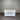 White wooden sideboard with three drawers and two doors against a corrugated metal wall.