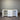 White storage unit with open doors and drawers against a corrugated metal wall.