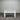 White wooden console table with two drawers against a corrugated metal wall.