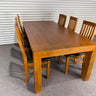 Wooden dining table with six chairs against a corrugated metal wall. wanaka collection