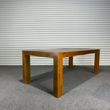Wooden dining table against a corrugated metal wall