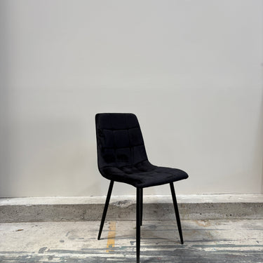 Modern black upholstered dining chair with metal legs, angled perspective