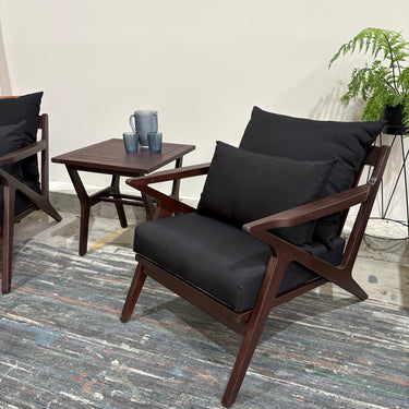 Close-up of Contemporary armchairs with black cushions and timber arms.