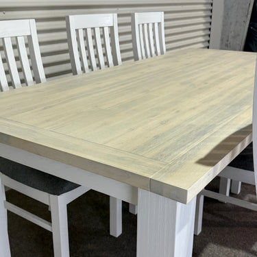 Wooden table with white chairs on a dark floor