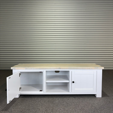 White TV stand with wooden top against a corrugated metal wall.