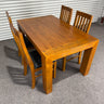 pine Wooden dining table with four chairs on a gray floor against a corrugated metal wall. wanaka collection