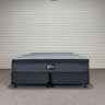 Workhorse LUX mattress king size with matching base, front view showing grey quilted top, dark upholstered base and caster feet against corrugated backdrop