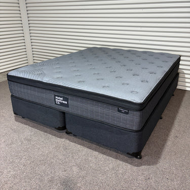 Top angled view of Workhorse LUX mattress with matching base, showing five-zone quilting pattern, cool-gel layer design and dark upholstered base against corrugated backdrop